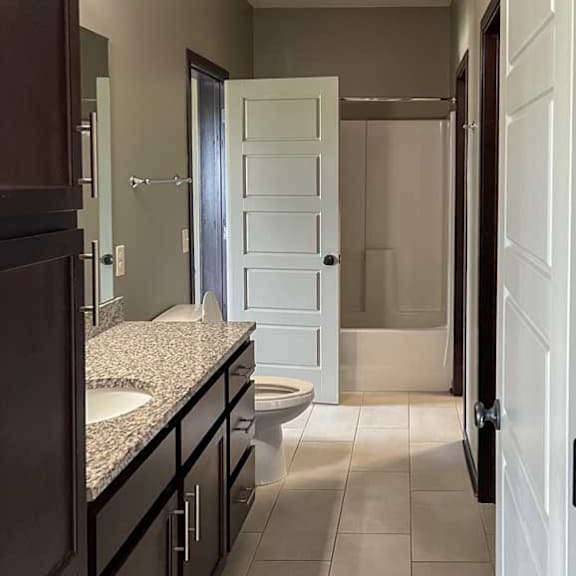 Thumbnail 11 of 20 a long bathroom with a wide vanity sink, mirror, a walk-in closet, and an attached laundry room