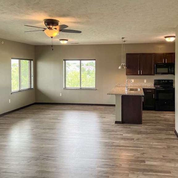 Thumbnail 3 of 20 a spacious living room with a kitchen area in the background