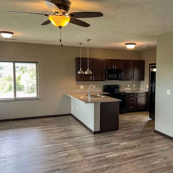 Thumbnail 4 of 20 a kitchen with a dark wooden cabinets, granite countertops, hardwood flooring, and two pendant lights