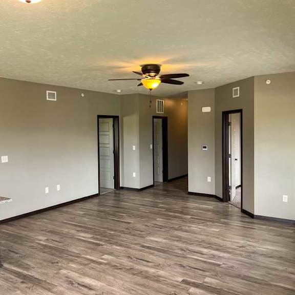 Thumbnail 7 of 20 a spacious living room with hardwood flooring, a ceiling fan, and a fireplace