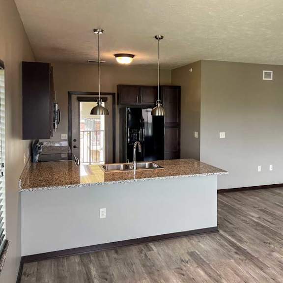 Thumbnail 6 of 20 a kitchen with a dark wooden cabinets, granite countertops, hardwood flooring, and two pendant lights