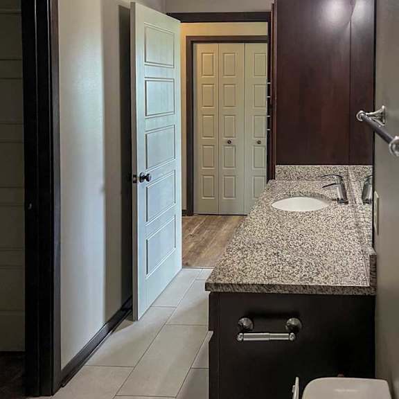 Thumbnail 16 of 20 a bathroom with a wide granite vanity sink and a tall storage cabinet