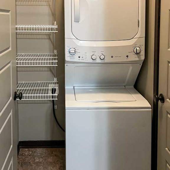 Thumbnail 15 of 20 a stackable washer and dryer in a laundry room attached to the bathroom with built-in shelving