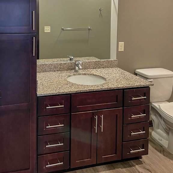 Thumbnail 12 of 13 a bathroom with a granite vanity sink, mirror, and tall storage cabinet