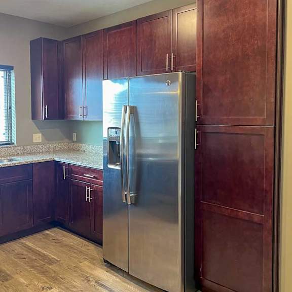 Thumbnail 6 of 13 a kitchen with warm wooden cabinets, granite countertops, hardwood flooring, and stainless steel appliances