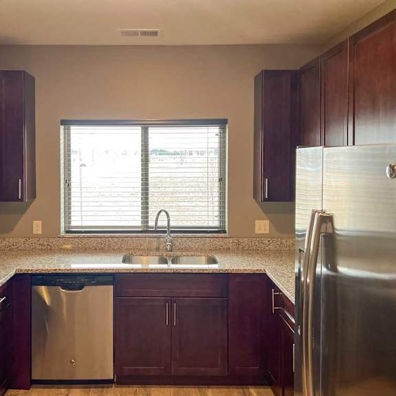 Thumbnail 7 of 13 a kitchen with warm wooden cabinets, granite countertops, hardwood flooring, and stainless steel appliances