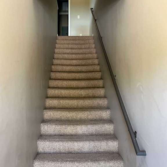 Thumbnail 2 of 15 a carpeted staircase and a handrail leading up to a laundry closet