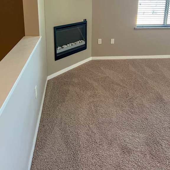 Thumbnail 6 of 15 a living room with carpeted flooring, several windows, a ceiling fan, and a fireplace