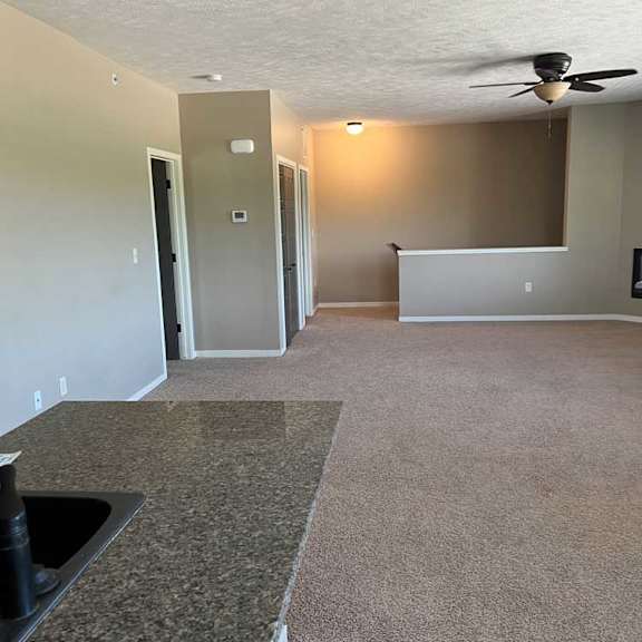 Thumbnail 10 of 15 a living room with carpeted flooring, a coat closet, a ceiling fan, stairs to the entryway, and a fireplace