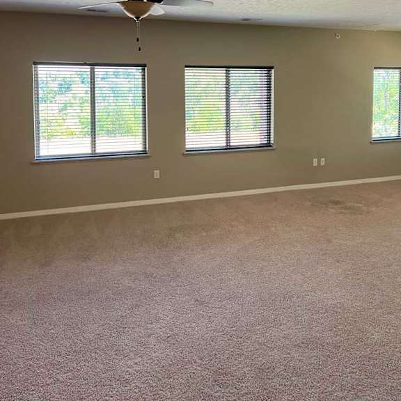 Thumbnail 7 of 15 a living room with carpeted flooring, several windows, and a ceiling fan