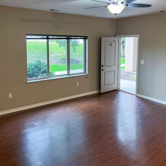 Thumbnail 3 of 35 a living room with hardwood flooring, a large window, and a fireplace