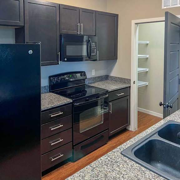 Thumbnail 6 of 35 a kitchen with dark wooden cabinets, granite countertops, and black appliances