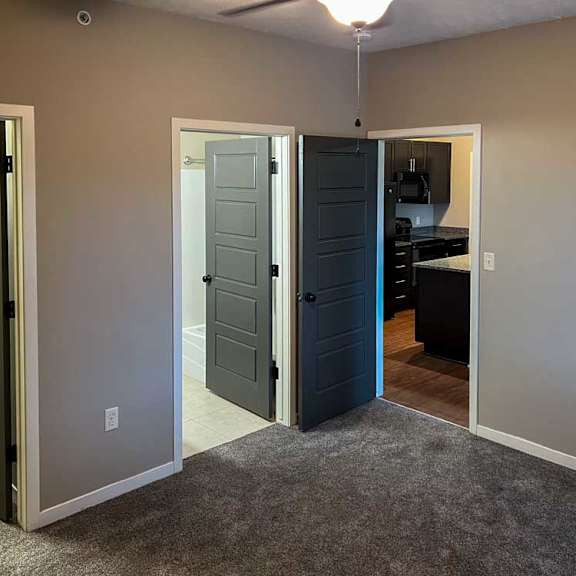 Thumbnail 8 of 35 a bedroom with carpeted flooring, a walk-in closet, an attached bathroom, and a ceiling fan