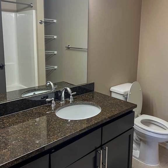 Thumbnail 10 of 35 a bathroom with a granite vanity sink and large mirror