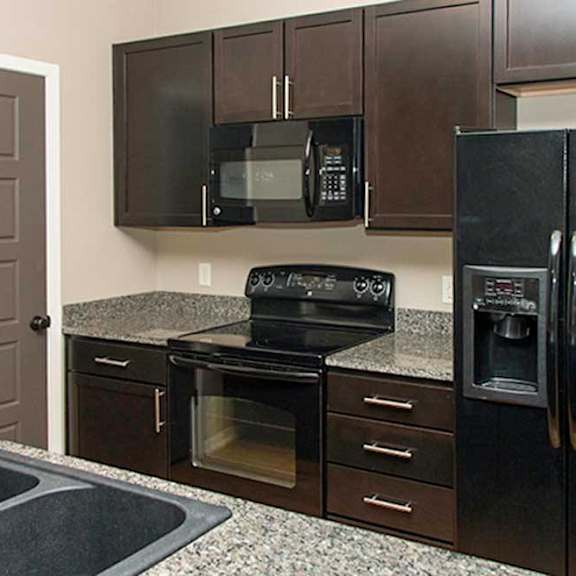 Thumbnail 31 of 35 a kitchen with dark wooden cabinets, granite countertops, and black appliances