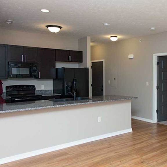 Thumbnail 30 of 35 a kitchen with dark wooden cabinets, granite countertops, hardwood flooring, and black appliances