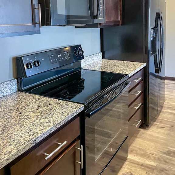Thumbnail 19 of 35 a kitchen with dark wooden cabinets, granite countertops, and black appliances