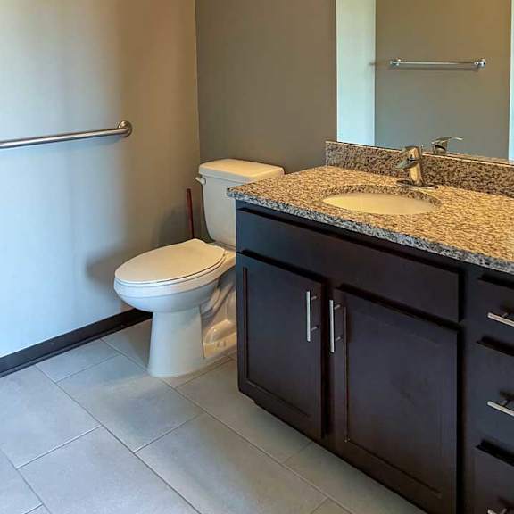 Thumbnail 23 of 35 a bathroom with a granite vanity sink and a tall mirror