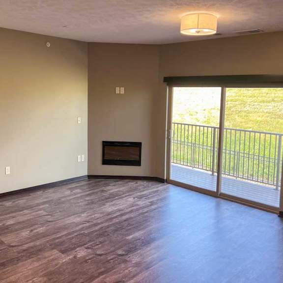 Thumbnail 12 of 19 a living room with a fire place and sliding glass doors to the balcony
