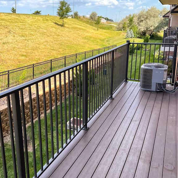 Thumbnail 11 of 19 a wooden deck with a black metal railing looking over a green space