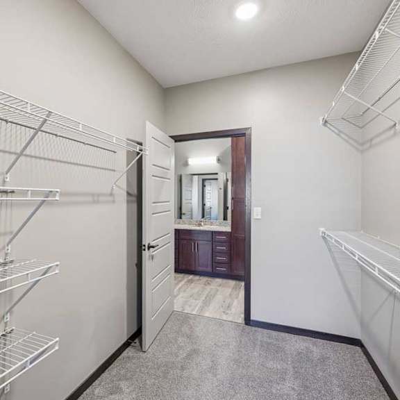Thumbnail 21 of 37 A walk-in closet with metal shelving and a mirrored door.