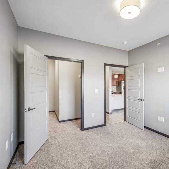 Thumbnail 49 of 51 A room with three doors and a carpeted floor.