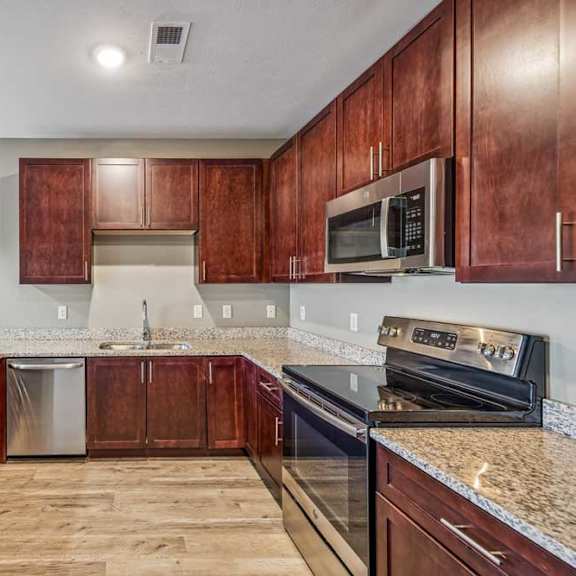 Thumbnail 35 of 51 A kitchen with wooden cabinets and granite countertops.