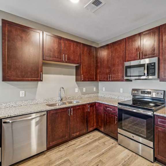 Thumbnail 42 of 51 A kitchen with wooden cabinets and stainless steel appliances.
