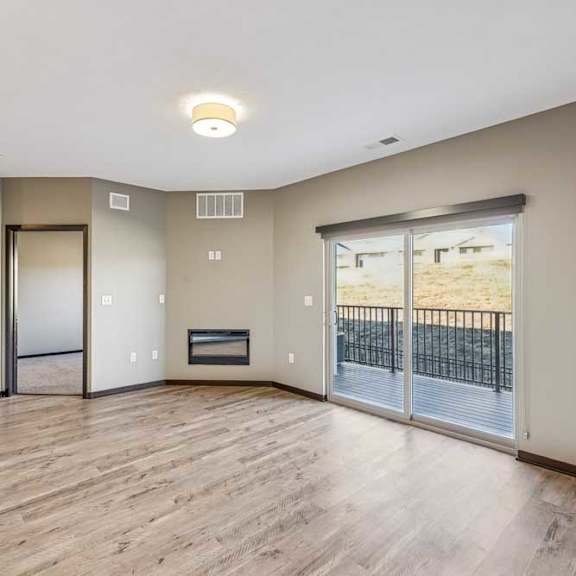 Thumbnail 40 of 51 A spacious room with wooden flooring and a sliding glass door leading to a balcony.