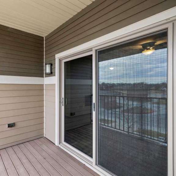 Thumbnail 25 of 33 A balcony with a sliding glass door leading to a patio.