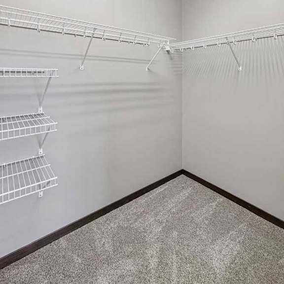 Thumbnail 18 of 33 Empty walk-in closet with white shelves and hangers.