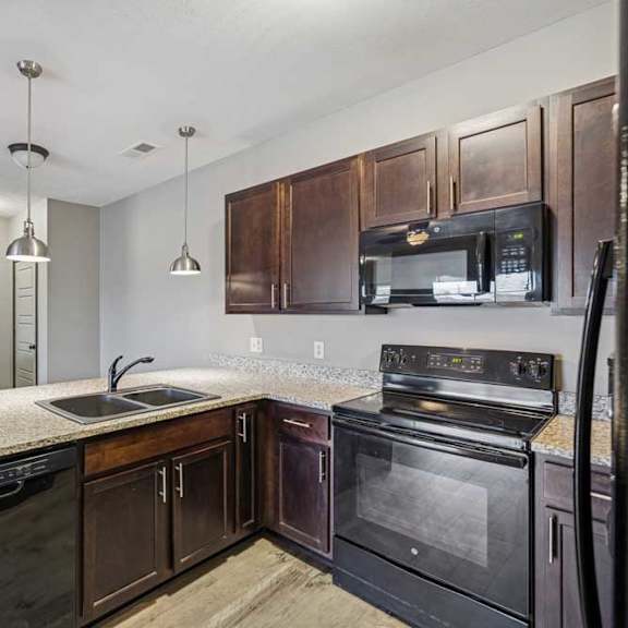 Thumbnail 31 of 33 A kitchen with dark wood cabinets and black appliances.