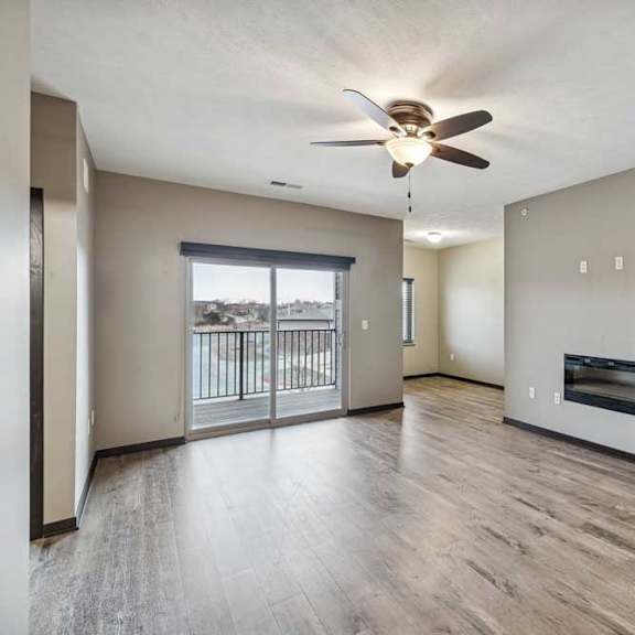 Thumbnail 17 of 33 A spacious room with a ceiling fan and a balcony with a railing.