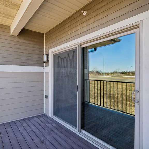 Thumbnail 9 of 16 A deck with a sliding glass door leading to a backyard.
