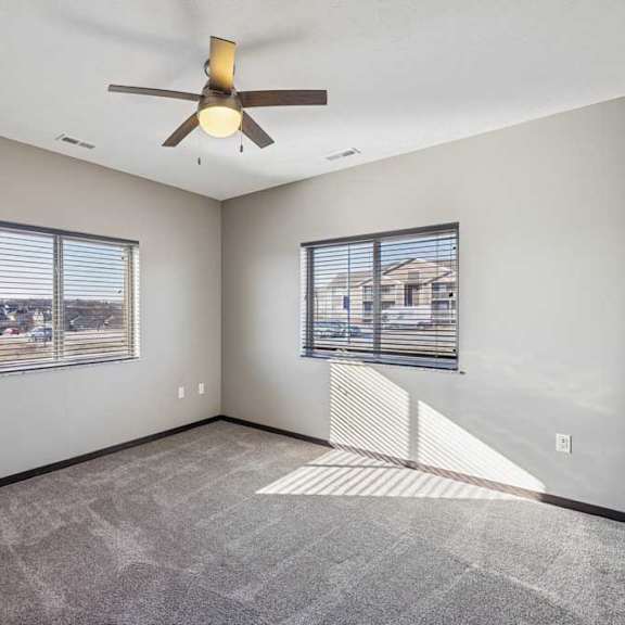 Thumbnail 6 of 16 A room with a ceiling fan and two windows.