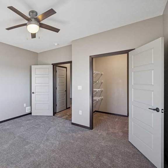 Thumbnail 13 of 16 A room with a ceiling fan and a door leading to another room.