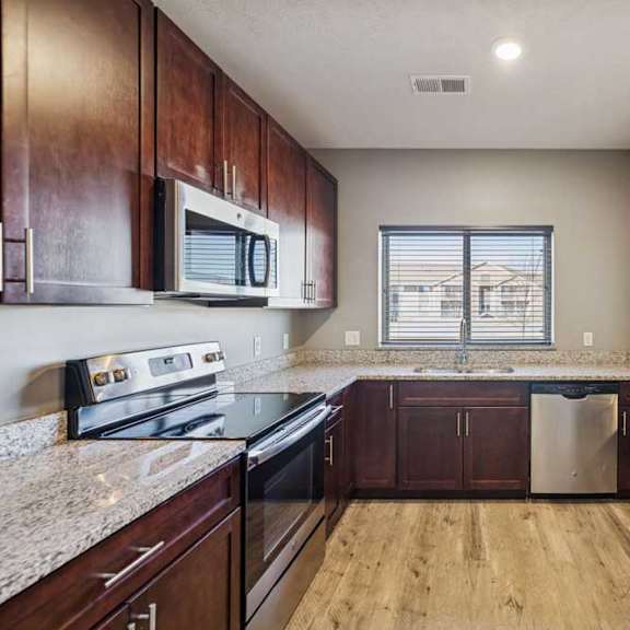 Thumbnail 12 of 16 A kitchen with wooden cabinets and granite countertops.