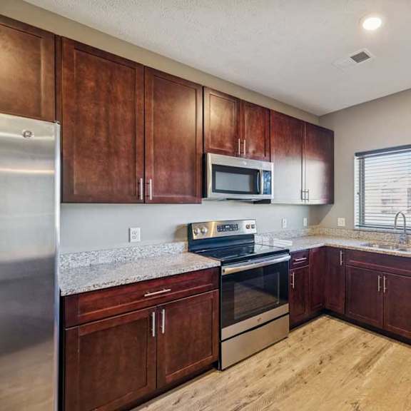 Thumbnail 4 of 16 A kitchen with wooden cabinets and stainless steel appliances.
