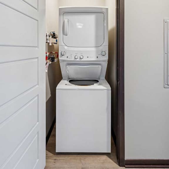 Thumbnail 15 of 16 A white washing machine and dryer in a small laundry room.