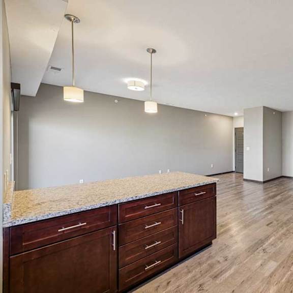 Thumbnail 10 of 16 A spacious room with wooden floors and a granite countertop.