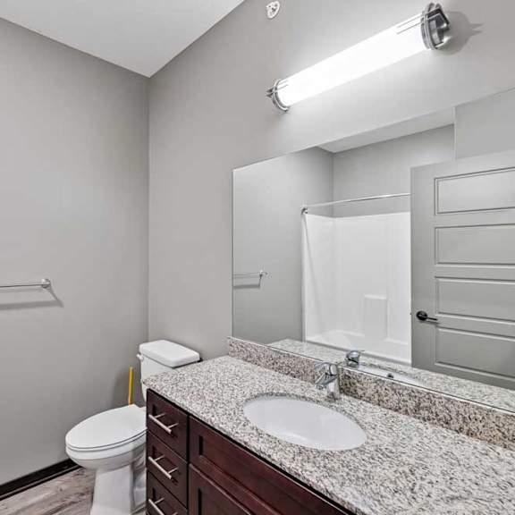 Thumbnail 13 of 22 A bathroom with a toilet, sink, and mirror.