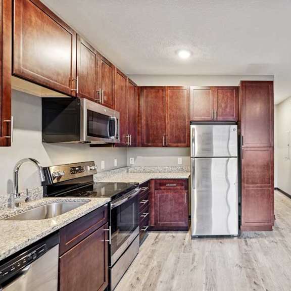 Thumbnail 14 of 22 A kitchen with wooden cabinets and stainless steel appliances.