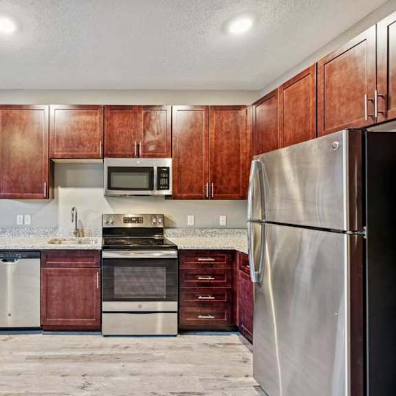 Thumbnail 16 of 22 A kitchen with wooden cabinets and stainless steel appliances.