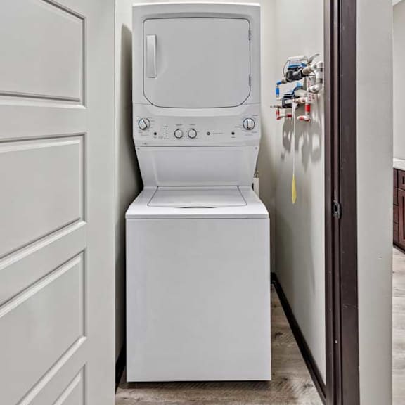 Thumbnail 15 of 22 A white washing machine is in a small space between two doors.