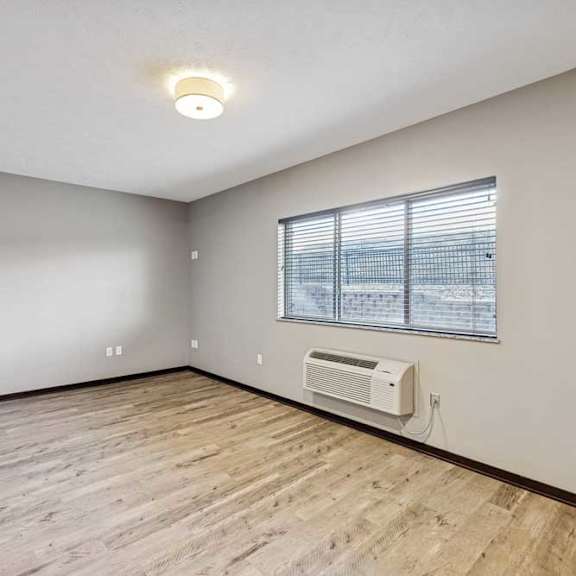Thumbnail 20 of 22 A room with a window, air conditioner, and wooden flooring.