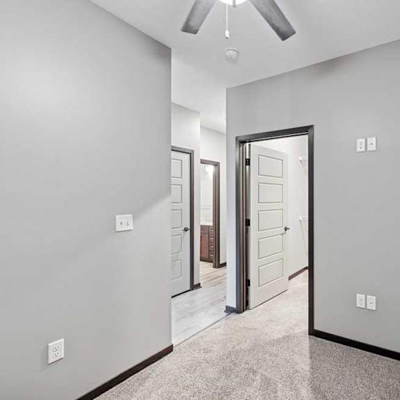 Thumbnail 18 of 22 A room with a ceiling fan and a carpeted floor.