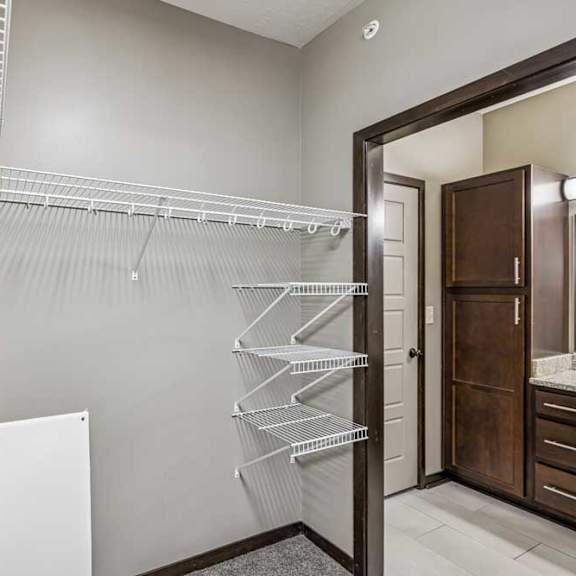 Thumbnail 38 of 45 A walk-in closet with a white metal rack and a white pedestal.