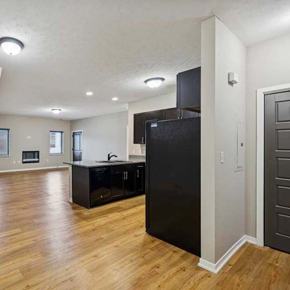 Thumbnail 9 of 45 A dining room open to a kitchen with dark cabinets, in front of a spacious living room.