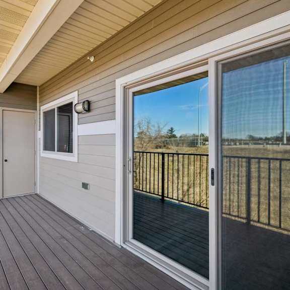 Thumbnail 20 of 43 A balcony with a sliding glass door and a wood floor.