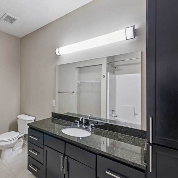 Thumbnail 13 of 22 A bathroom with a wide granite vanity sink, tall storage cabinet, and oversized mirror.